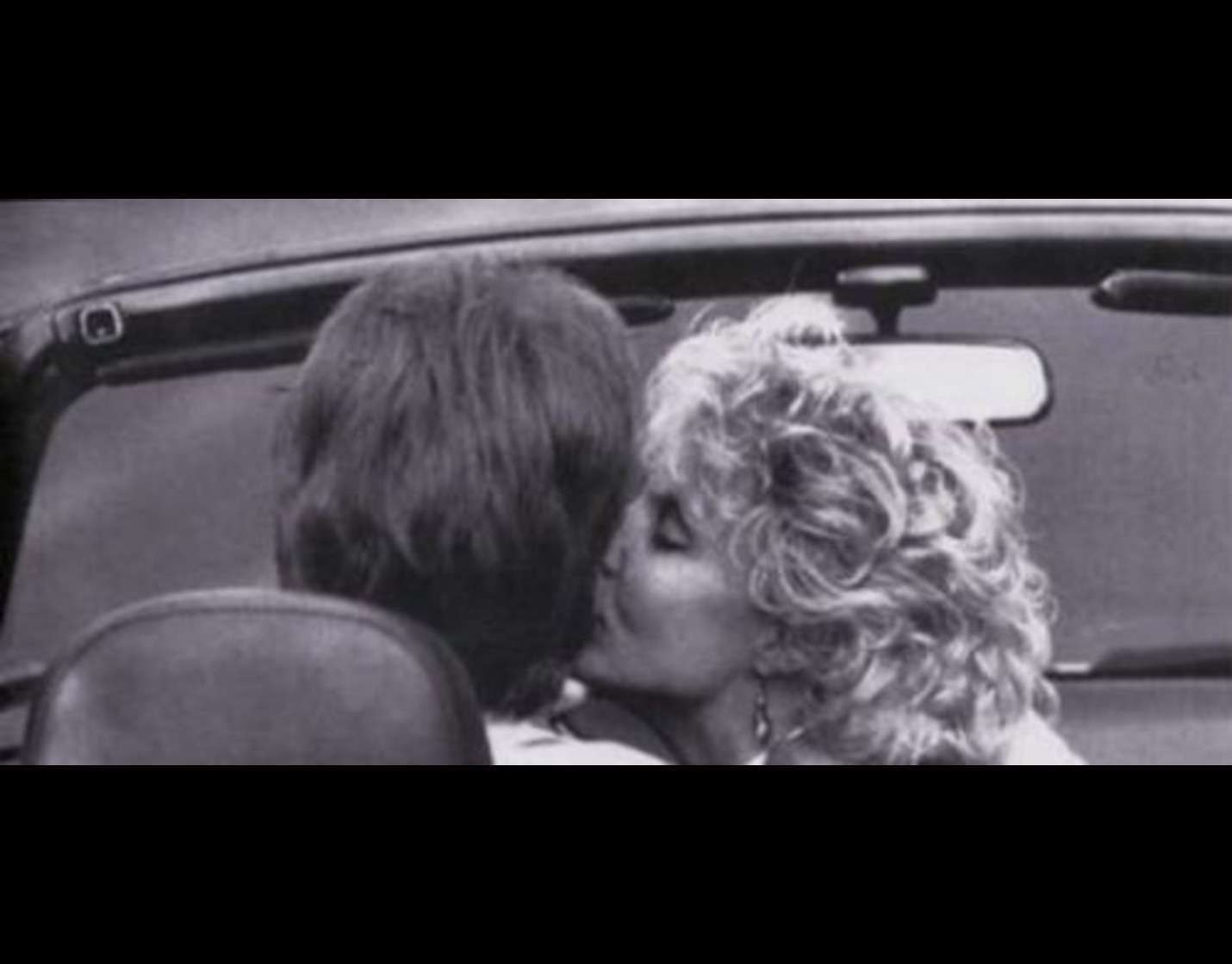 Black-and-white photo of a couple kissing in a convertible