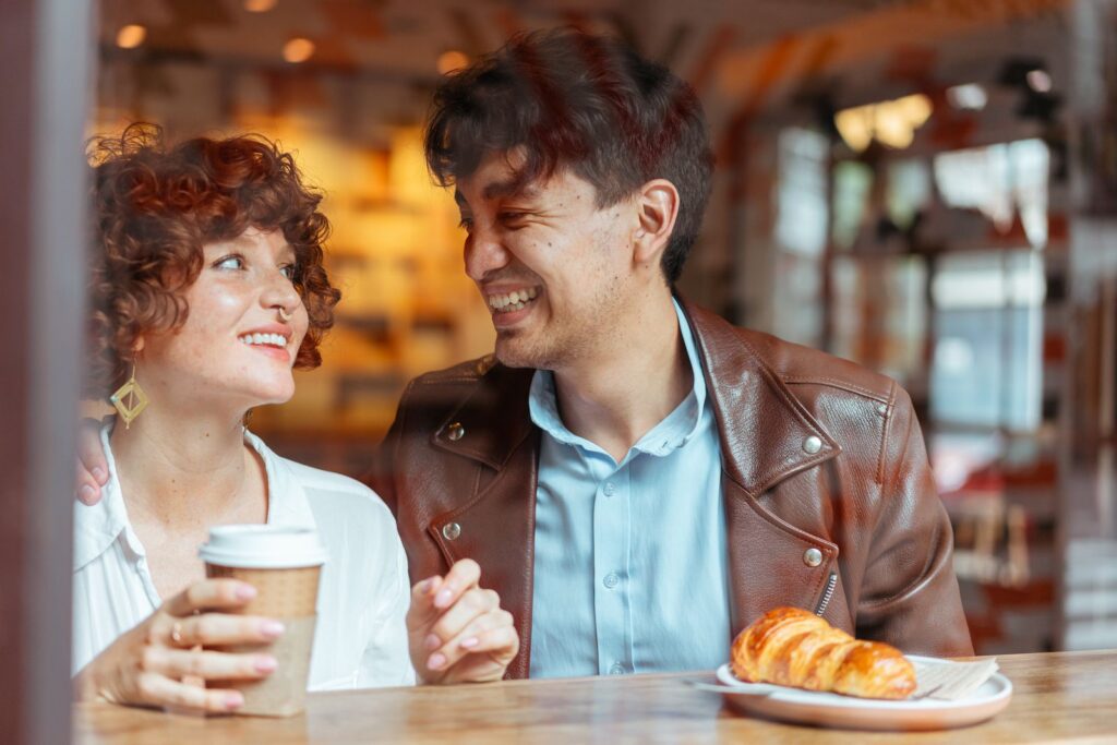 Young couple laughing together on a date while enjoying coffee at a cafe