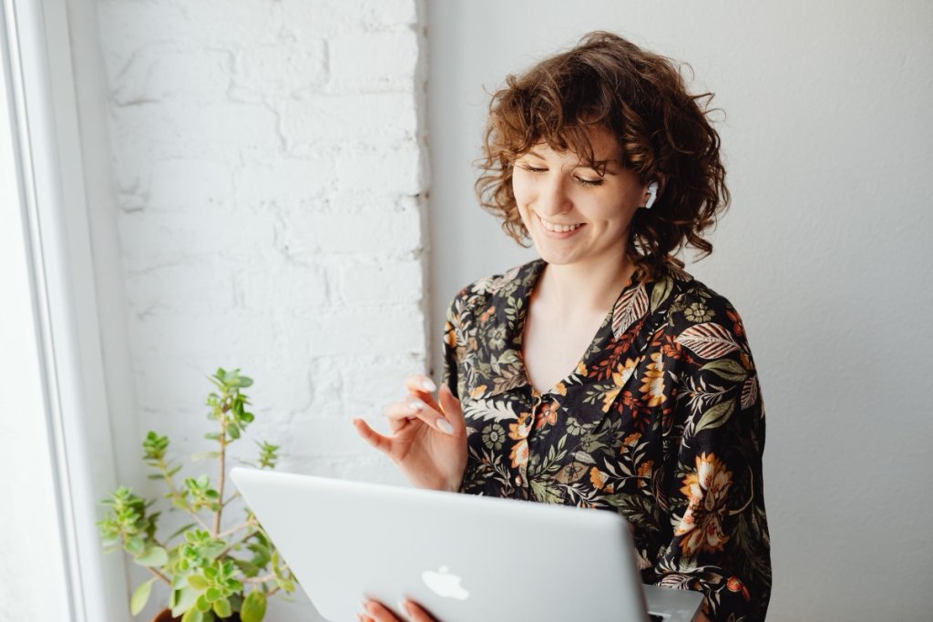 A woman smiling at her laptop during a video coaching session at home