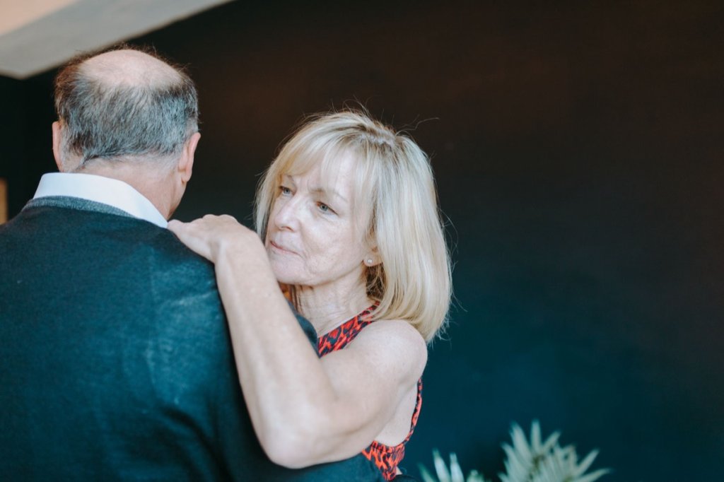 A couple in their sixties dancing together at home