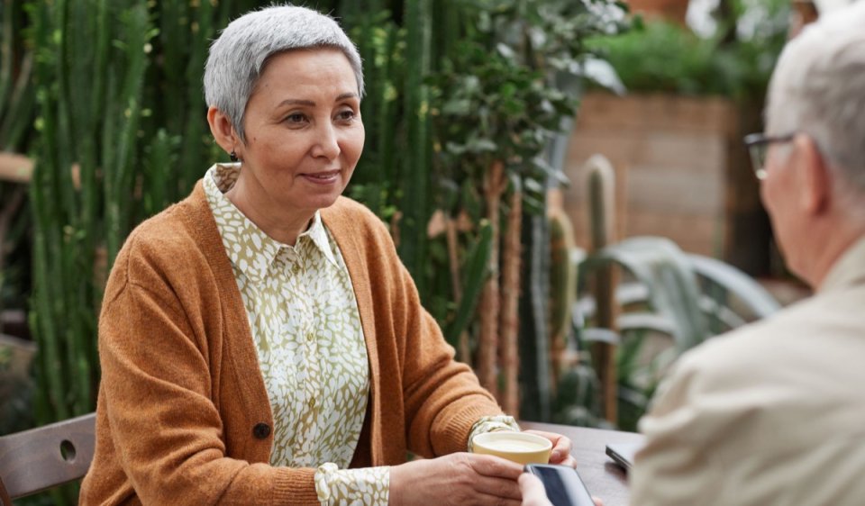 An older couple talking over coffee at a garden cafe
